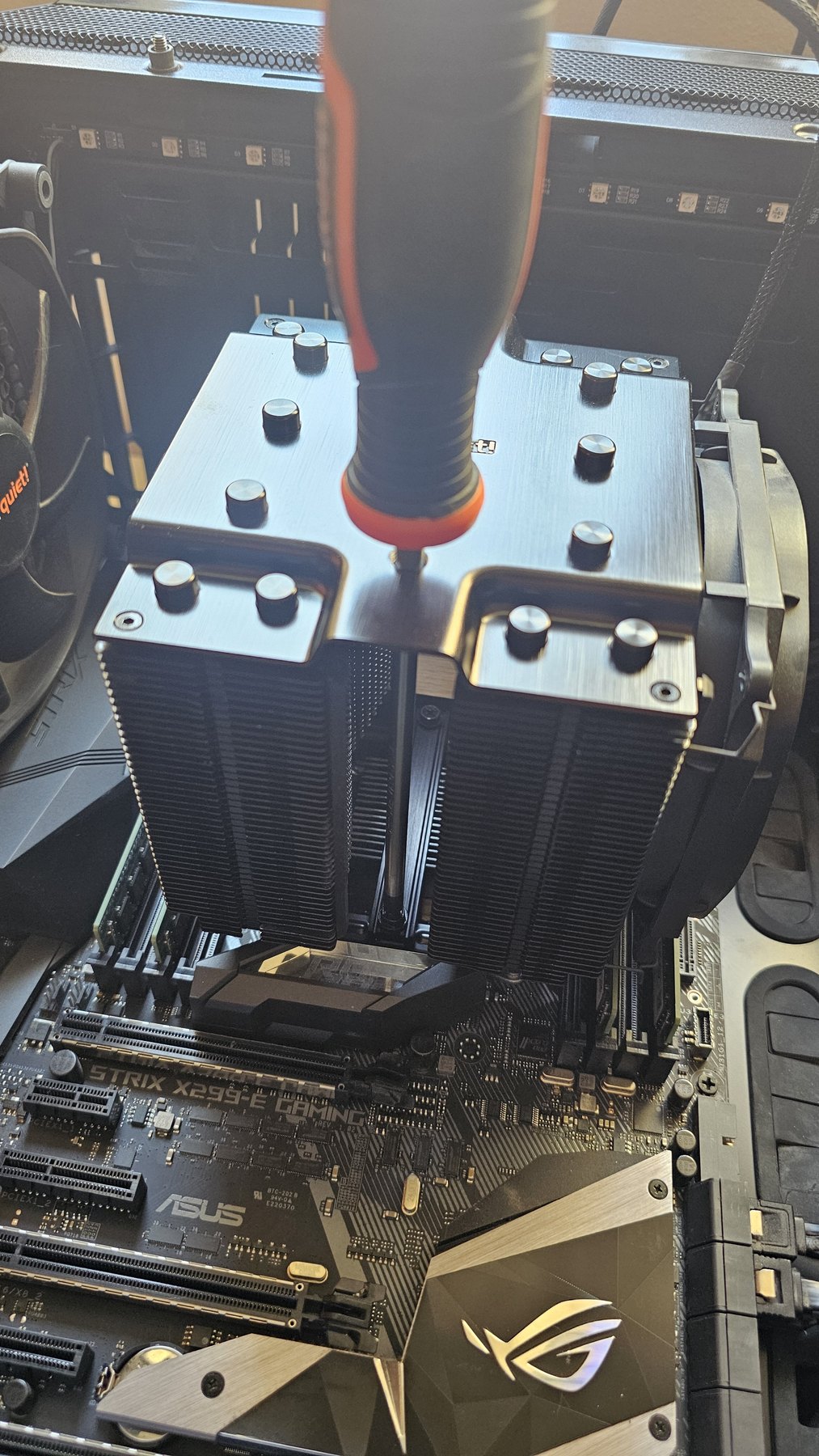 A large dual-tower CPU cooler being screwed onto a motherboard