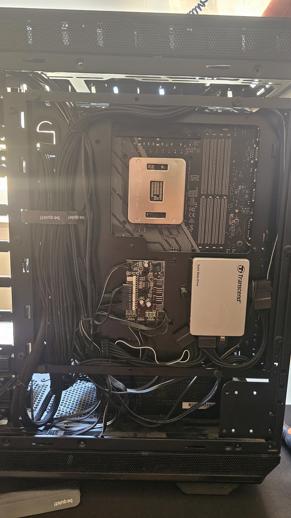The rear compartment of a PC case with routed cables and a 2.5 inch SSD