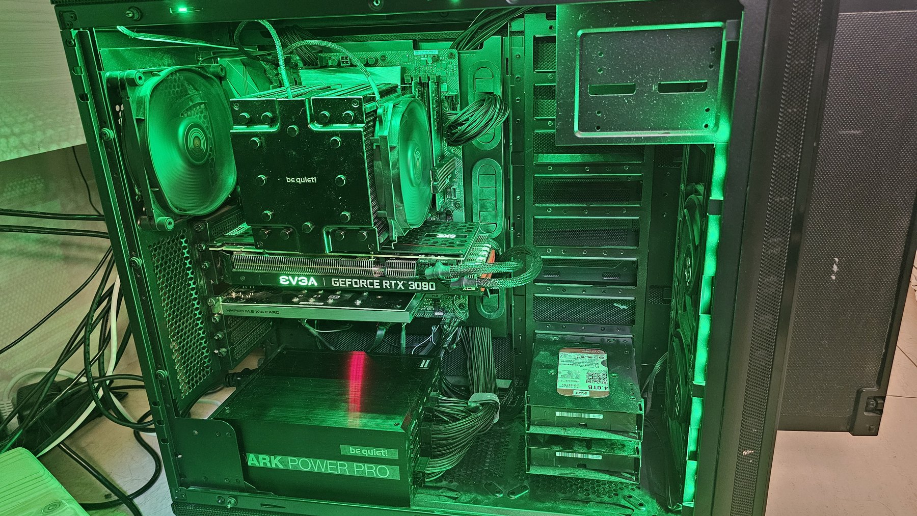 The interior of a PC case lit green, showing an EVGA GeForce RTX 3090 and a be quiet! Dark Power Pro power supply